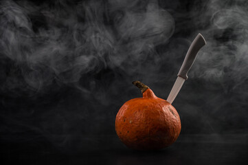 Wall Mural - A knife in a pumpkin in the smoke. Happy Halloween.