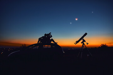 Wall Mural - Couple stargazing together with a astronomical telescope.