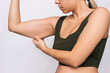 © Марина Демешко - Cropped shot of a young caucasian blonde woman grabbing skin on her upper arm with excess fat isolated on a gray background. Pinching the loose and saggy muscles. Taking care of the body