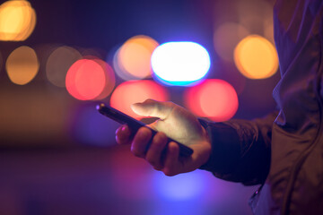 Wall Mural - man holding smart phone in bokeh background