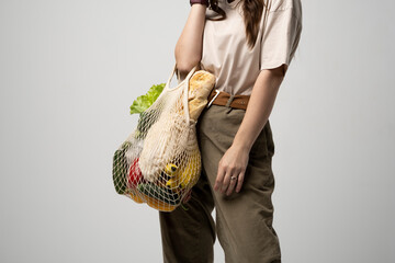 Wall Mural - Portrait of smiling young woman in oversize t-shirt holding reusable string bag with groceries. Reusable eco bag for shopping. Zero waste, plastic free concept. Eco lifestyle. Eco shopping.