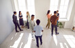 © Studio Romantic - Diverse people talking in groups during a meeting. High angle shot of different young community members or company employees standing in a modern office room, discussing something, sharing opinions