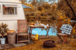 trailer of mobile home or recreational vehicle stands on shore of pond in camping in autumn near table set, concept of family local travel in native country on caravan or camper van and camping life
