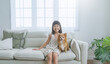 © paulaphoto - Portrait of cute young little asian woman playing with lovely friendly dog. Pretty cheerful girl in siting with a dog on sofa, lifestyle in living room. Childhood education concept