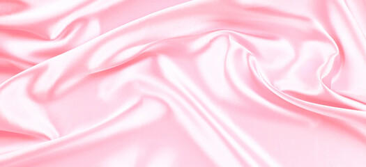 Beautiful pastel pink background with drapery and wavy folds of silk satin material texture. Top view