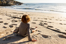 Young Boy Sitting On A Sandy Beach