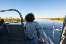 A Boy On A Motorboat Travelling Along A Waterway In The Okavango Delta