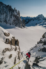 Wall Mural - Climber rappeling down an alpine peak. Winter mountaineering, alpinism in Mont Blanc Masiff, France. An alpinist descending on a rope from a mountain.