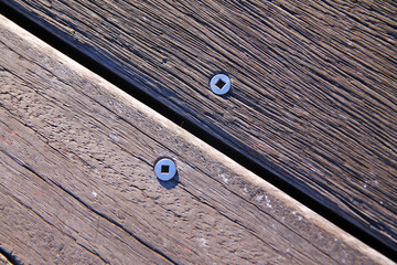 Screws and nails on two wood steps of different trees