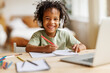 © JenkoAtaman - Smiling african american child school boy in headphones studying online on laptop at home