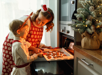 Happy family mother and son taking freshly baked Christmas cookies from oven