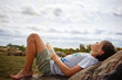 © Cavan Images - A young boy lays back on rock barefoot in sunshine