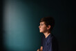 © Cavan Images - Portrait of a sad young boy against a dark blue wall.