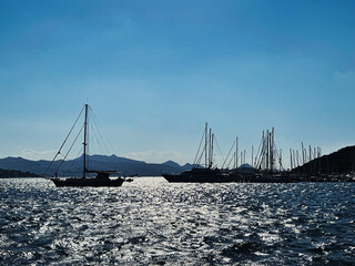 Wall Mural - Tranquil seascape and coastal nature concept. Sea, boats, mountains and blue sky over horizon at sunset.