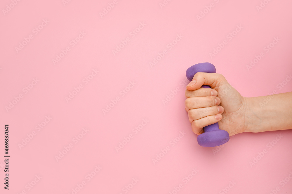 Female hand with dumbbell on pink background