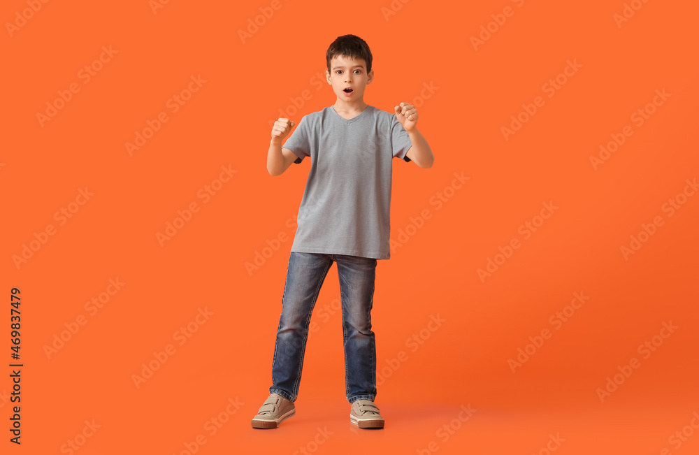 Shocked little boy with imaginary steering wheel on color background