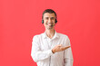Male consultant of call center with headset showing something on red background