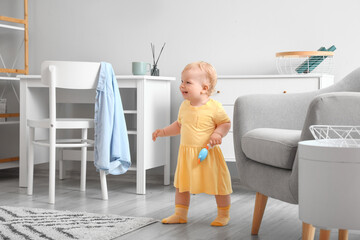 Canvas Print - Cute baby girl in yellow dress with toy learning to walk at home