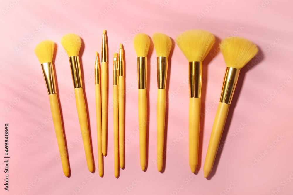 Set of stylish makeup brushes on pink background