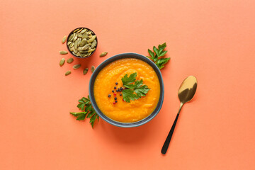 Bowl with delicious pumpkin cream soup and seeds on color background