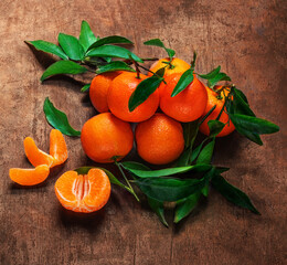 Wall Mural - Mandarines oranges fruits or tangerines with green leaves on a dark wooden background. Copyspace.