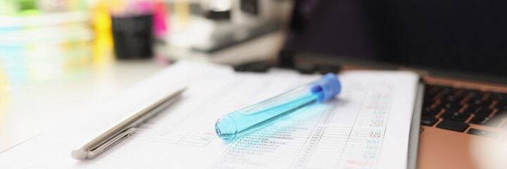 Vial of blue liquid lies on test results document closeup