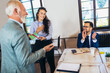 © Mediteraneo - Businesswoman receiving award from businessman in front of business professionals, applauding at business seminar in office building