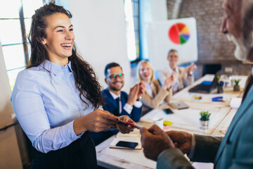businesswoman receiving award from businessman in front of business professionals, applauding at bus