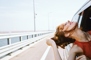 Wall Mural - cheerful woman peeking out of the car window trip road travel