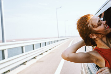 Wall Mural - cheerful woman peeking out of the car window trip road travel