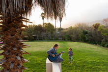 Teenage Girl Playing Guitar And Singing Outdoors