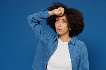 Wall Mural - Young sick tired exhausted ailing black woman in casual clothes shirt white t-shirt put hand on forehead have headache isolated on plain dark blue background studio portrait. People lifestyle concept.