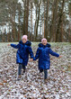Two twin girls runing down hill covered with first snow