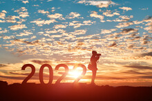 Silhouette Of Photographer Taking Photos In 2022 Years At Sunrise Or Sunset Background. Idea For Happy New Year 2022.