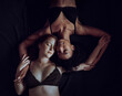 © Lomb - Couple of homosexual women in lingerie lying eyes closed in the bed. Multiracial lesbians relaxin in the bed, dark moody image.