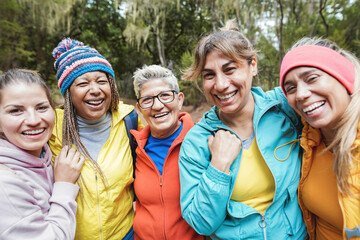 Wall Mural - Multiracial female friends having fun during trekking mountain day into the woods - Travel and vacation concept - Focus on center senior face