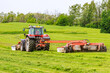 A tractor with two rotary mowers mows the grass. Mowers in front and behind the tractor