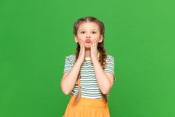 Wall Mural - The little girl grabbed her cheeks and made a sponge tube. Child on a green isolated background. Copy space.