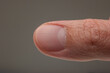 Caucasian male thumb and fingernail macro close up studio shot, isolated on gray