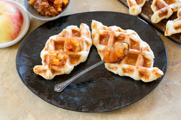 Croffle is an Asian delicacy made of puff pastry with apple jam. Delicious waffles on a ceramic plate close-up..