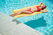 Enjoying suntan. Vacation concept. Top view of slim young woman in bikini on the yellow air mattress in the swimming pool.