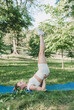 © Tatsiana - the girl performs complex yoga exercises in the park on a gym mat. the concept of a healthy lifestyle