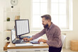 © Studio Romantic - Busy financial accountant using computers and calculator while working in office workplace. Young man sitting at desk, looking at laptop, preparing financial documents, using online chat and calendar