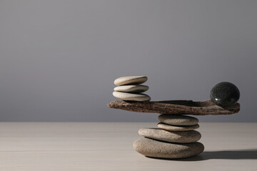 Stack of stones with tree branch on wooden table, space for text. Harmony and balance concept