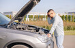 © Julija - Man with broken car in the middle of the road looking to engine of automobile.