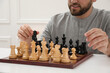 © New Africa - Man playing chess at white table indoors, closeup