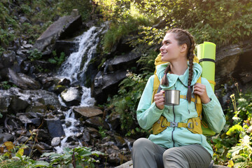 Sticker - Tourist with cup near waterfall in mountains. Space for text