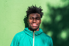 Portrait Of Smiling Black Boy On Green Wall Background.
