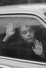 Little Boy Looking Out Of Car Window In The Rain