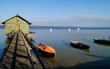 a long wooden pier leading to the colorful boat houses on lake Ammersee in the German fishing village Schondorf (Germany)	
